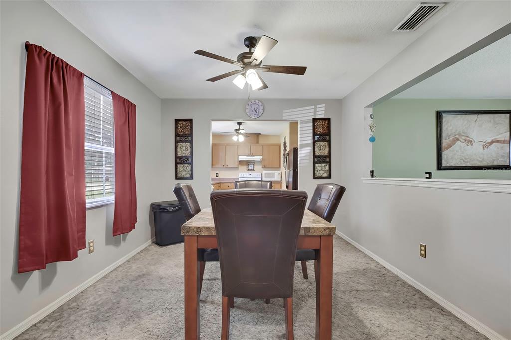 A dining room features a stone-topped table, dark leather chairs, and a ceiling fan — 7499 WABASH TRAIL, SPRING HILL, FL