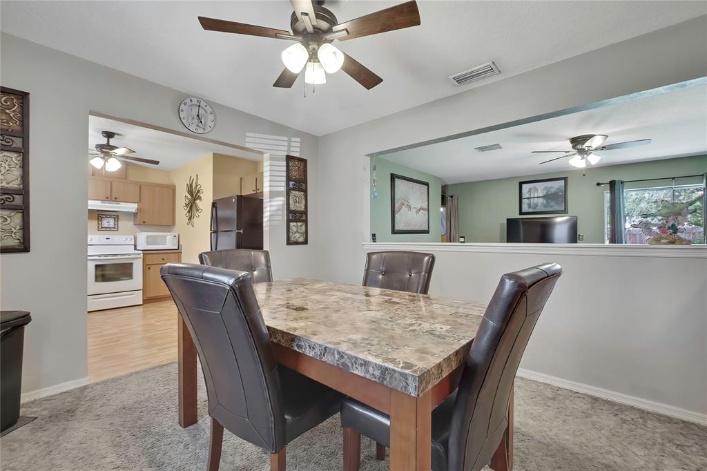 A dining room with a marble-topped table, dark leather chairs, and a ceiling fan — 7499 WABASH TRAIL, SPRING HILL, FL