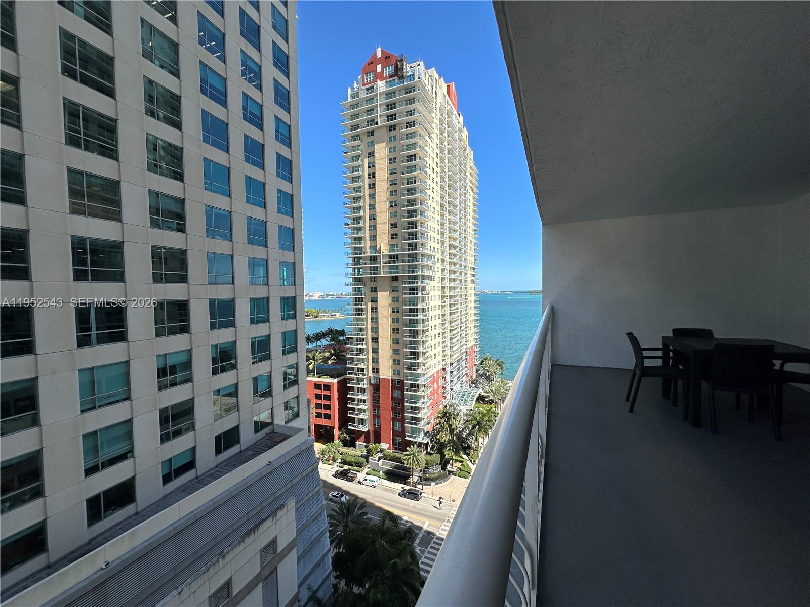 A balcony view overlooks a street, a tall residential building, and the ocean — 1200 Brickell Bay Dr # 1712, Miami FL 33131, MIAMI, FL