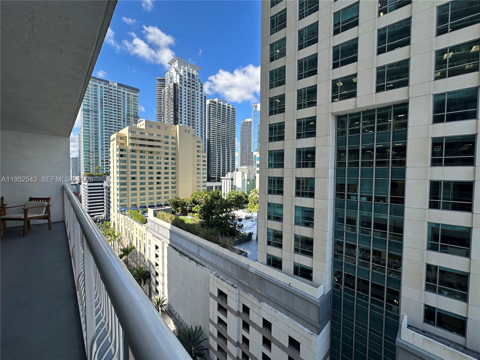 A balcony with a chair overlooks a dense urban skyline with several high-rise buildings — 1200 Brickell Bay Dr # 1712, Miami FL 33131, MIAMI, FL