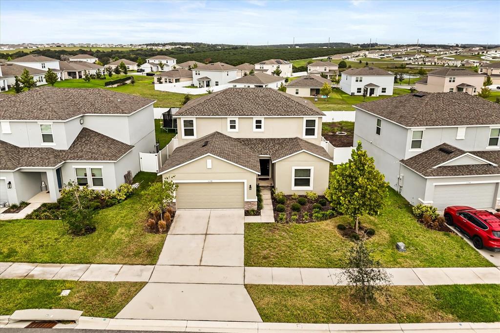 An aerial view shows a two-story suburban house with a tan exterior and a driveway — 1138 CALICO POINTE CIRCLE, GROVELAND, FL