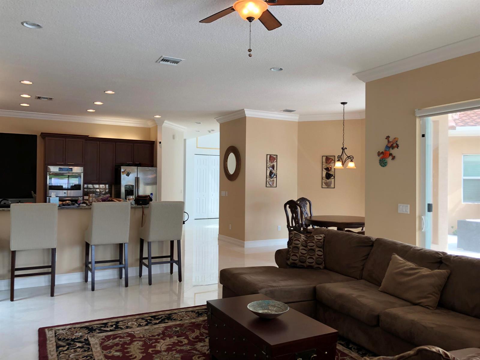 An open-concept living area features a kitchen with dark cabinetry, a dining nook, and sofa — 7793 Arbor Crest Way, West Palm Beach FL 33412, WEST PALM BEACH, FL