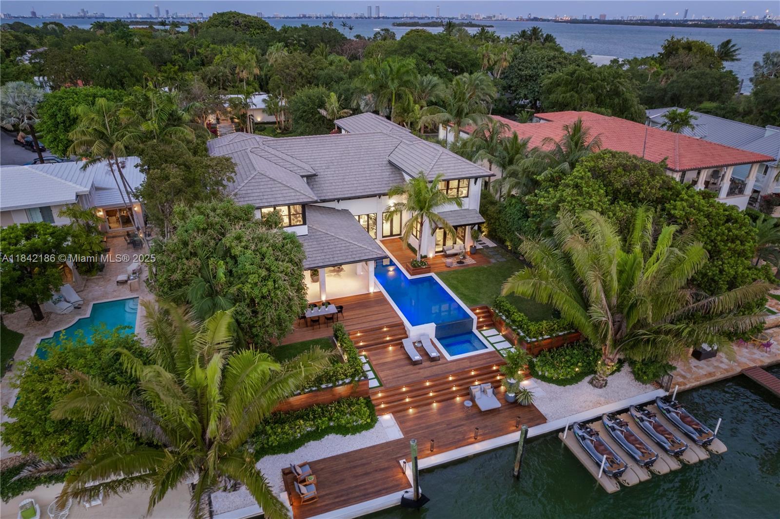 An aerial view shows a waterfront house with a pool, wooden deck, and boat lifts — 4241 Palm Ln, Miami FL 33137, MIAMI, FL