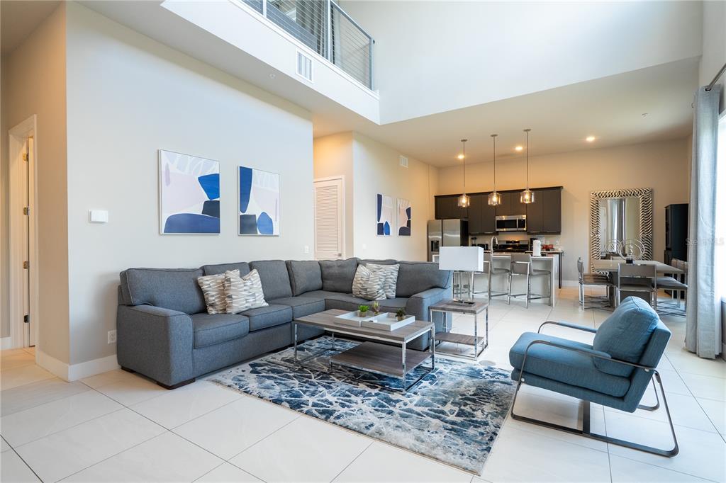 A living room with a gray sectional sofa, blue accent chair, and open kitchen area — 7740 SANDY RIDGE DRIVE UNIT 247, REUNION, FL