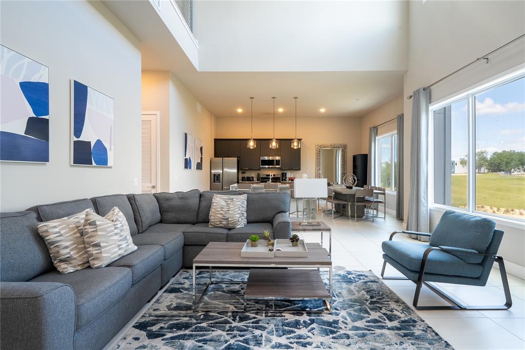 A living room with a sectional sofa, area rug, and an open kitchen in back — 7740 SANDY RIDGE DRIVE UNIT 247, REUNION, FL