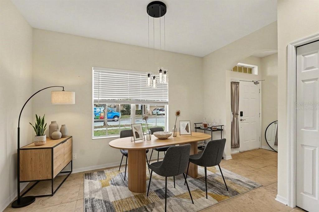 A dining room features a wooden oval table, gray chairs, and a modern pendant light — 7610 TANGLE BROOK BOULEVARD, GIBSONTON, FL