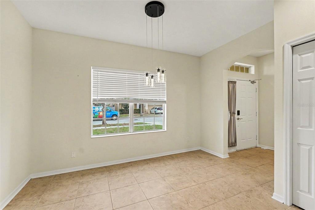 A dining area with tile flooring, a modern pendant light, and a window facing outside — 7610 TANGLE BROOK BOULEVARD, GIBSONTON, FL