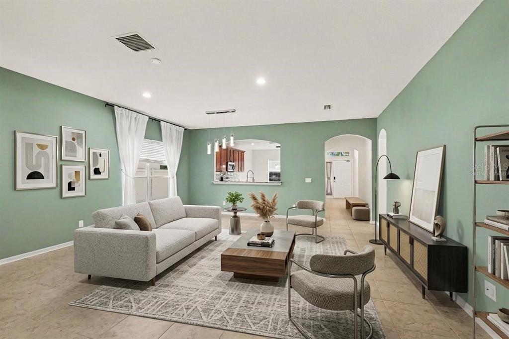 A living room with sage green walls, a gray sofa, and a modern coffee table — 7610 TANGLE BROOK BOULEVARD, GIBSONTON, FL