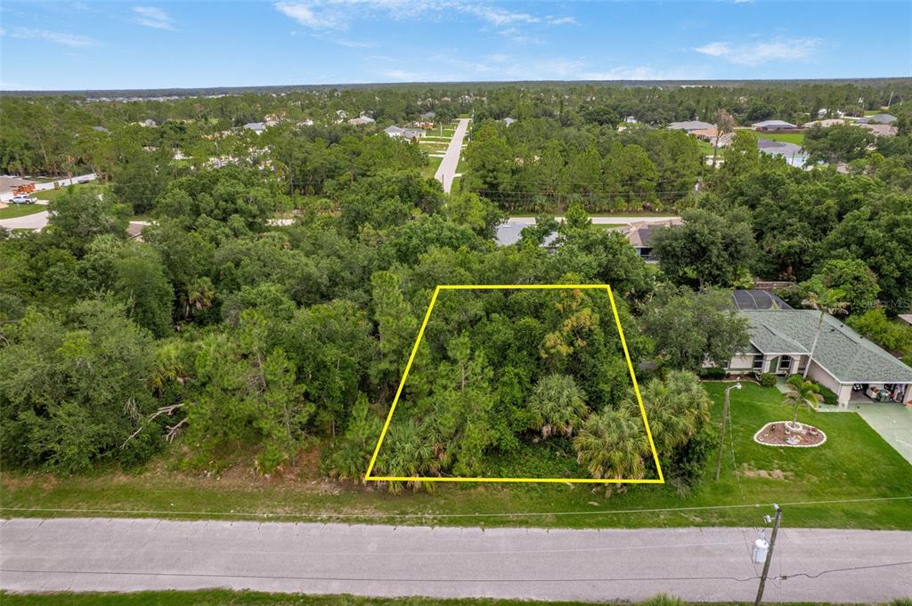 An aerial view shows a vacant, tree-covered residential lot outlined in yellow beside a house — VAN LEER AVENUE, NORTH PORT, FL