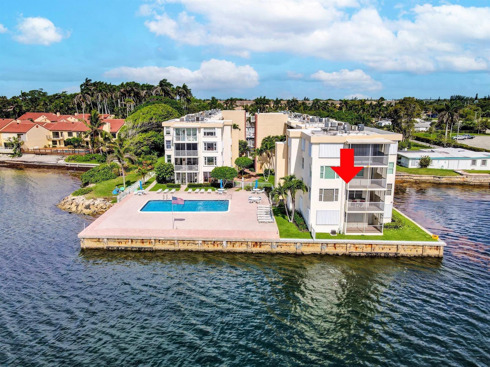 An aerial view of a waterfront apartment building with a pool and a marked balcony — 1820 New Palm Way # 201, Boynton Beach FL 33435, BOYNTON BEACH, FL