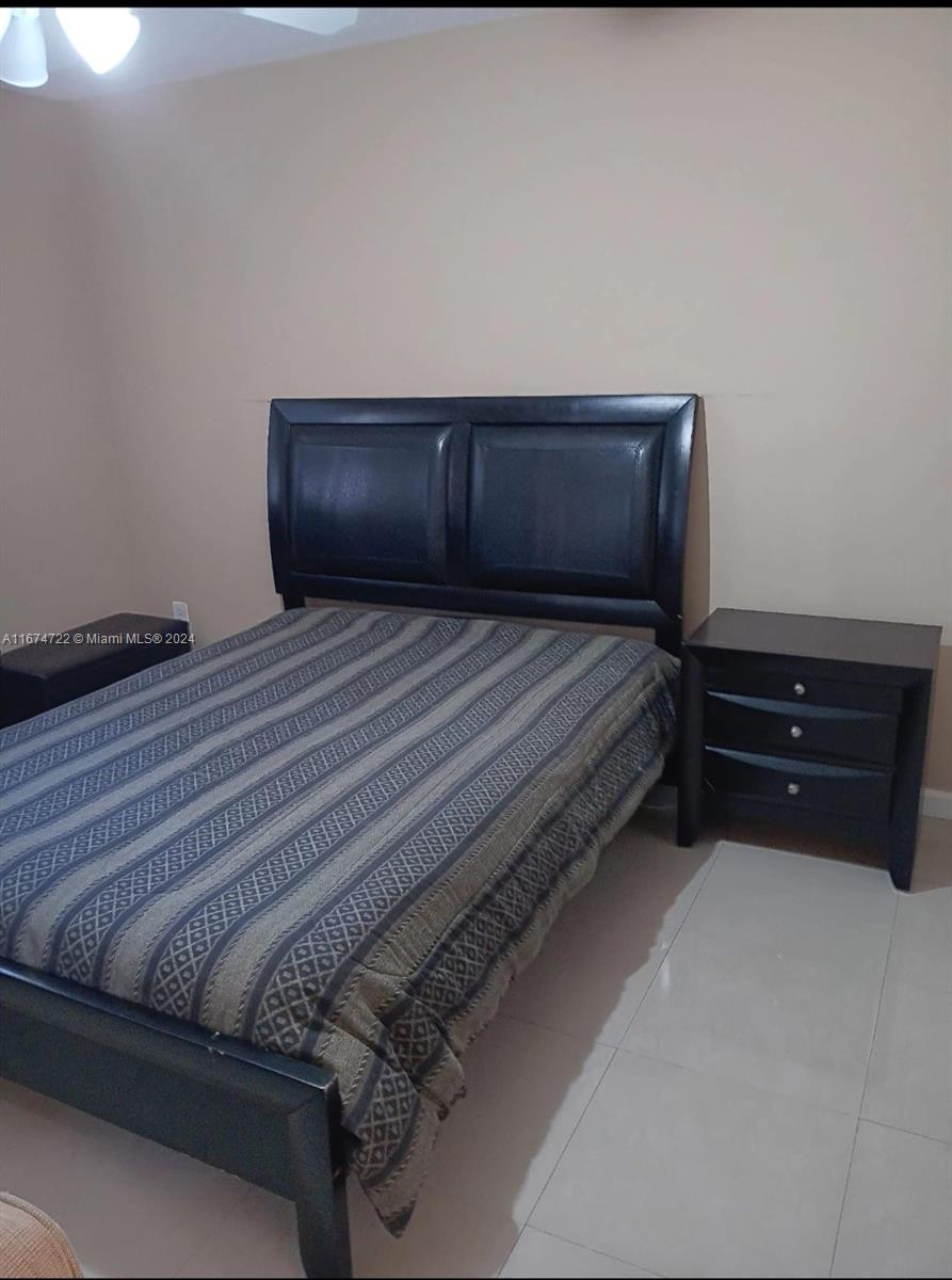 A bedroom features a black bed frame, a matching nightstand, and a patterned bedspread — 18870 NW 57th Ave # 108, Hialeah FL 33015, HIALEAH, FL