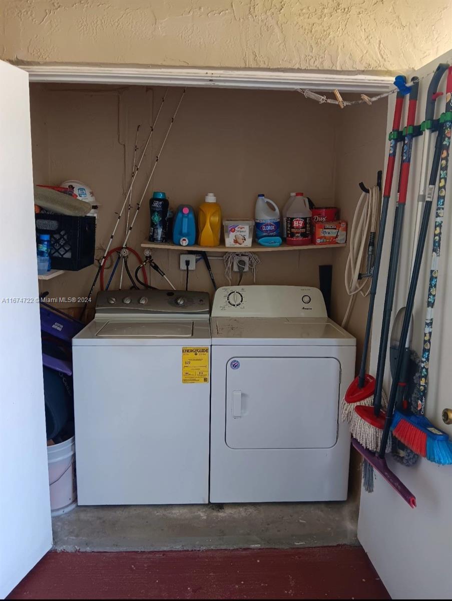 A laundry closet contains a white washer and dryer with a shelf for cleaning supplies — 18870 NW 57th Ave # 108, Hialeah FL 33015, HIALEAH, FL