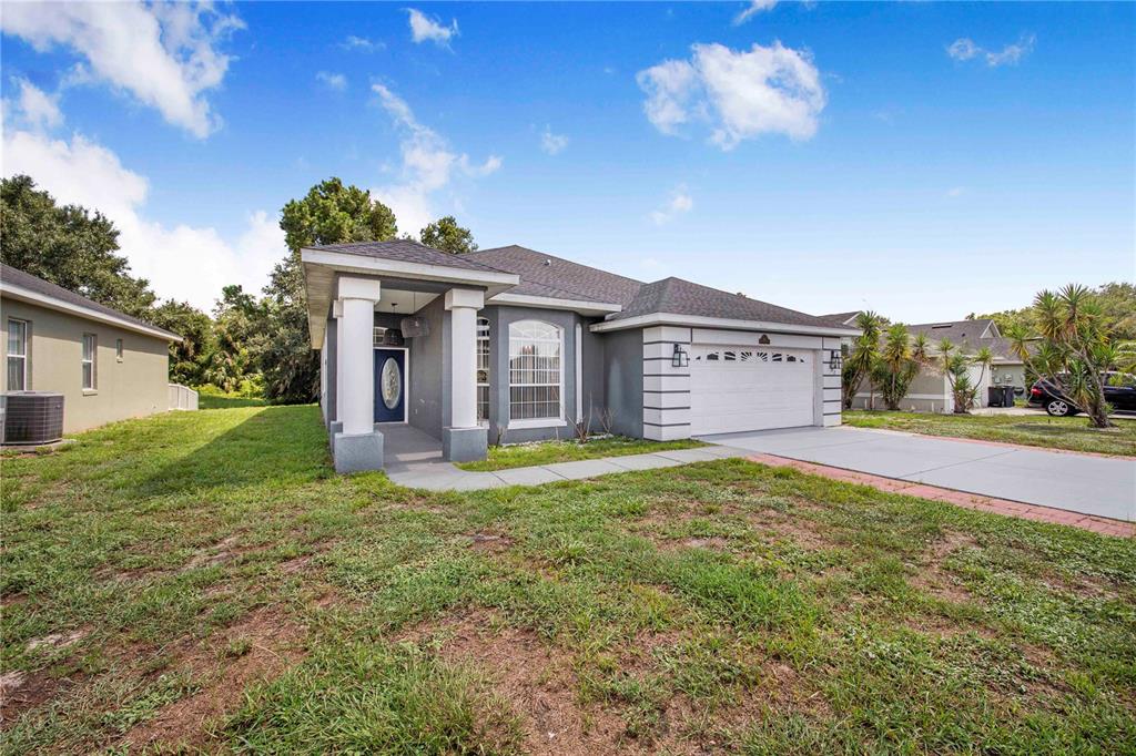 A single-story house with a gray exterior, white columns, and a two-car garage — 132 GOLF AIRE BOULEVARD, HAINES CITY, FL