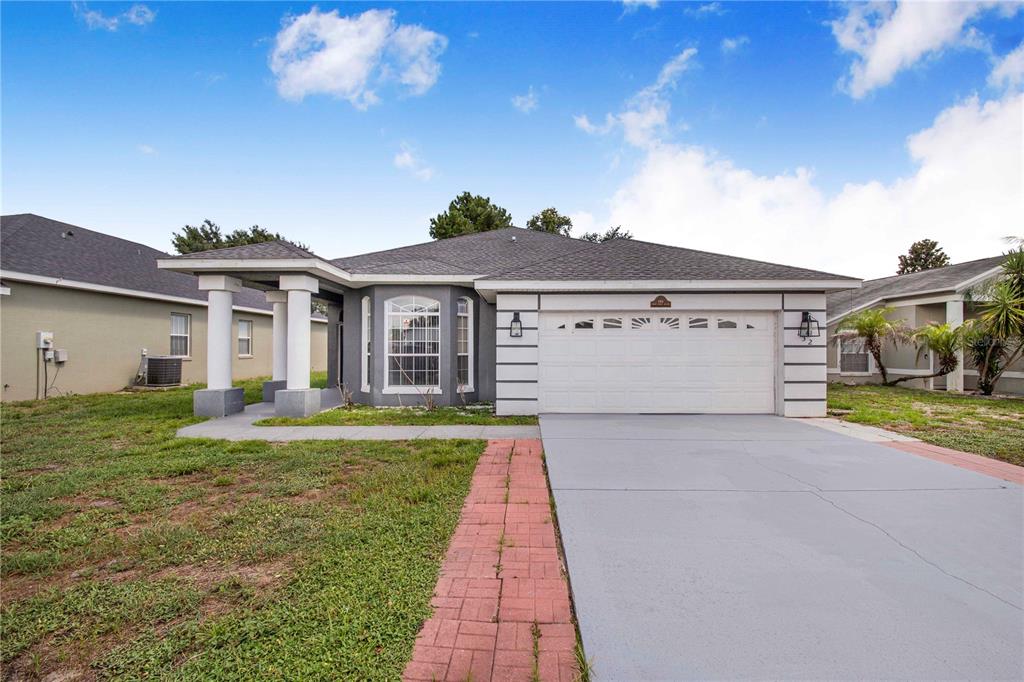 A single-story house with a gray exterior, a two-car garage, and a brick walkway — 132 GOLF AIRE BOULEVARD, HAINES CITY, FL