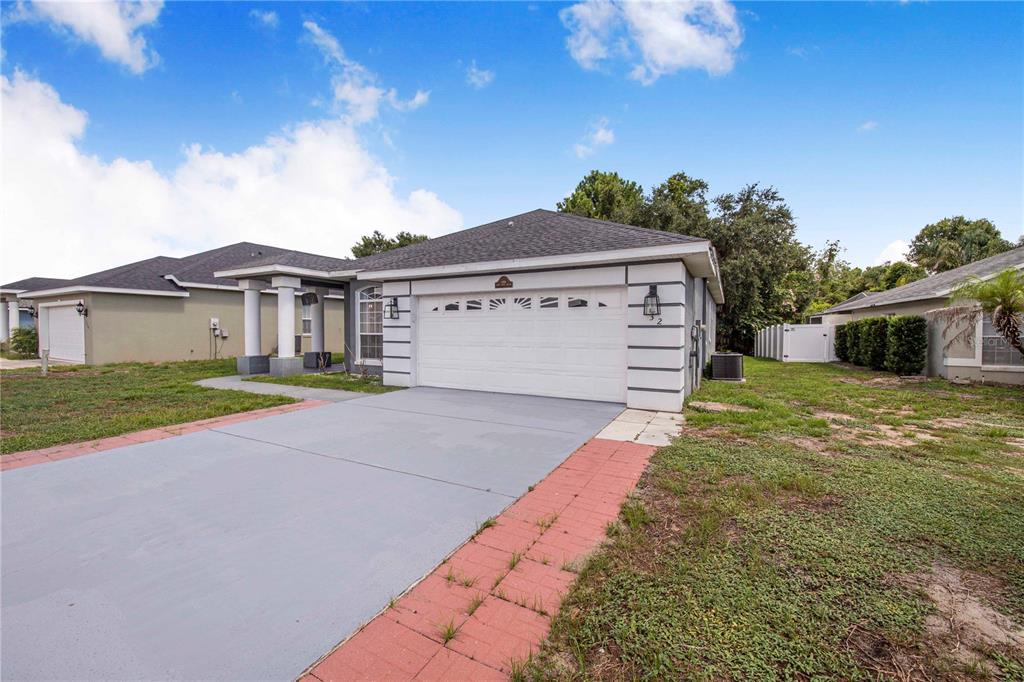 A single-story house with a white garage door, gray driveway, and red brick walkway — 132 GOLF AIRE BOULEVARD, HAINES CITY, FL