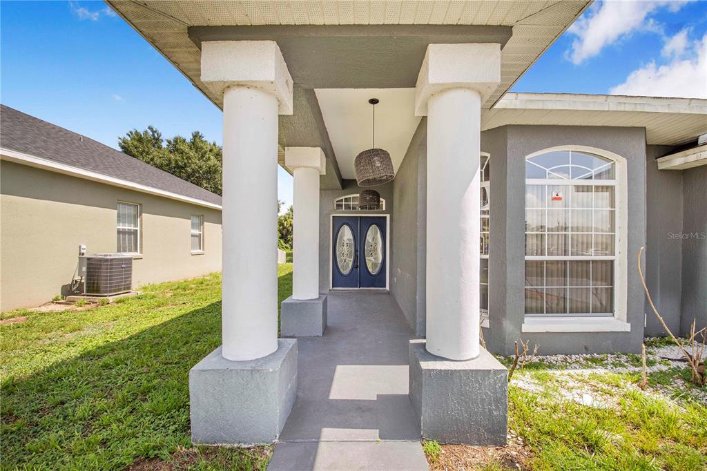 A covered front porch features white columns and a blue double door entrance — 132 GOLF AIRE BOULEVARD, HAINES CITY, FL