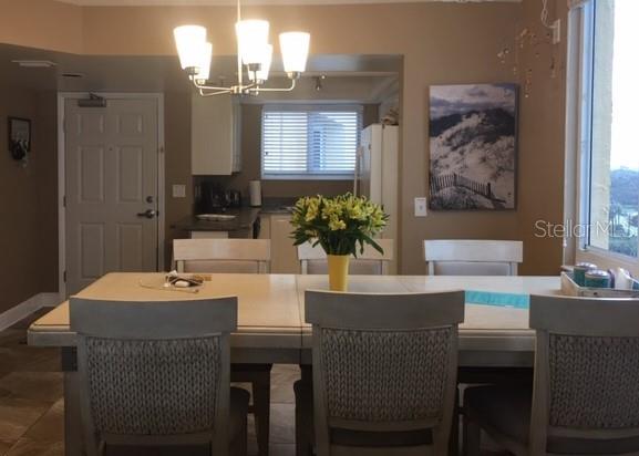 A dining area features a light-colored table, upholstered chairs, a chandelier, and an adjacent kitchen — 421 SOUTH ATLANTIC AVENUE UNIT 806, NEW SMYRNA BEACH, FL