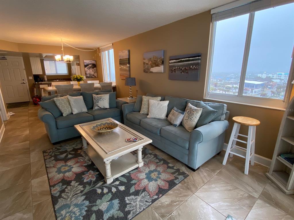 A living room features two blue sofas, a floral rug, and a large window view — 421 SOUTH ATLANTIC AVENUE UNIT 806, NEW SMYRNA BEACH, FL