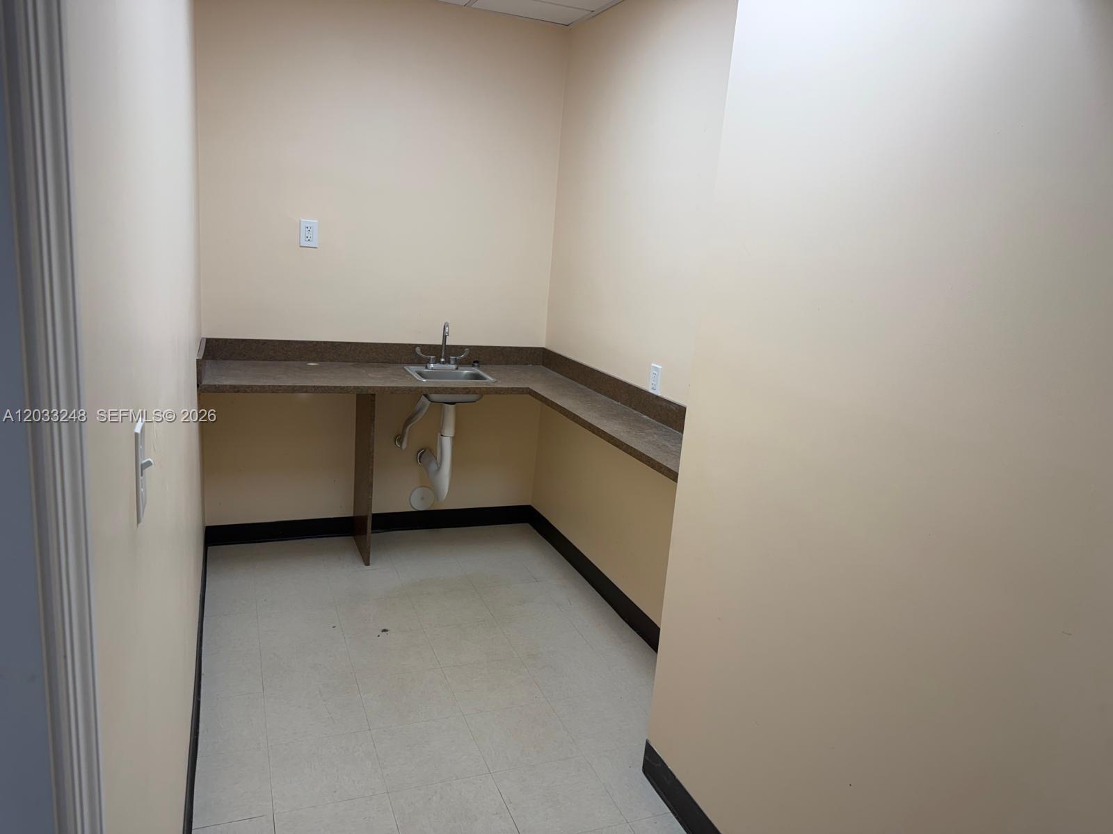 A small room features a corner countertop with a stainless steel sink and beige walls — 8688 NW 44 ST, Sunrise FL 33351, SUNRISE, FL