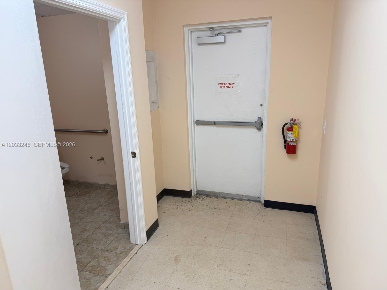 A hallway leads to a bathroom on the left and an emergency exit door — 8688 NW 44 ST, Sunrise FL 33351, SUNRISE, FL
