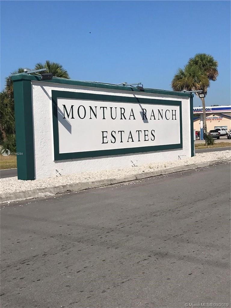 A white sign with dark green trim displays the text Montura Ranch Estates — 470 N Cabbage Palm Street, Clewiston FL 33440, CLEWISTON, FL