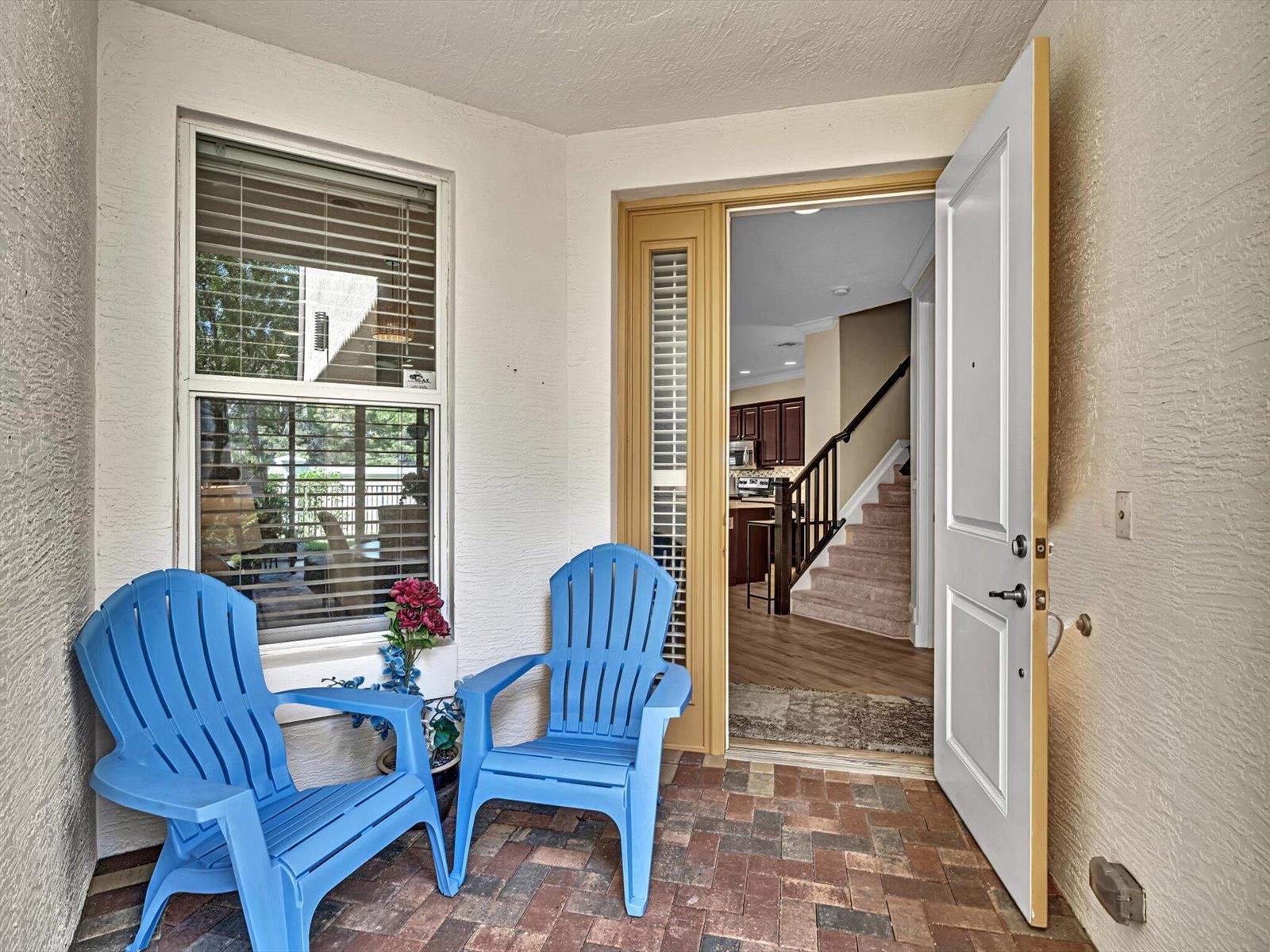 A small brick patio features two blue Adirondack chairs and an open front door — 4865 NW 16th Terrace, Boca Raton FL 33431, BOCA RATON, FL