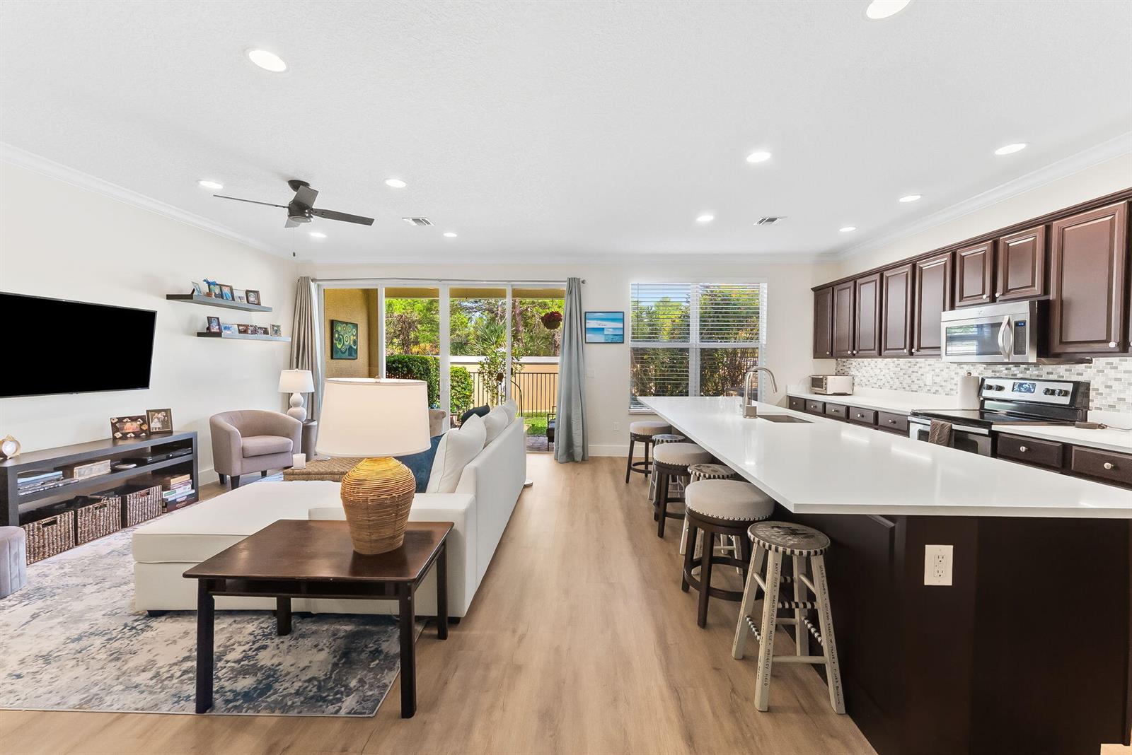 An open-concept living room and kitchen feature dark wood cabinets, white countertops, and sliding doors — 4865 NW 16th Terrace, Boca Raton FL 33431, BOCA RATON, FL