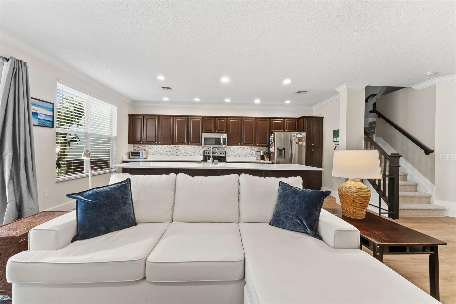 A white sectional sofa faces a kitchen with dark wood cabinets and a white island — 4865 NW 16th Terrace, Boca Raton FL 33431, BOCA RATON, FL