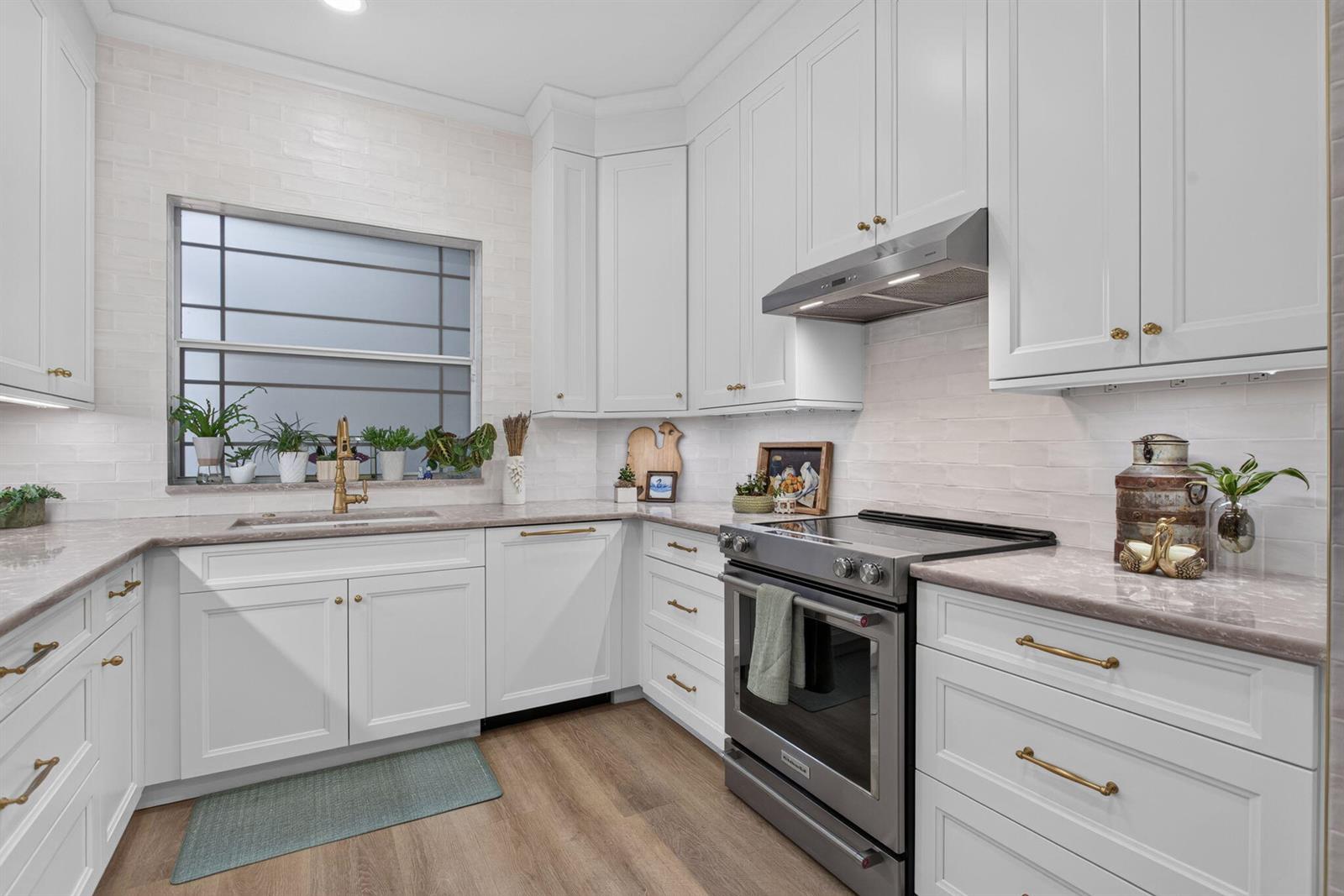 A white kitchen features light-colored countertops, stainless steel appliances, and a window above the sink — 2505 NE 2nd Street, Pompano Beach FL 33062, POMPANO BEACH, FL