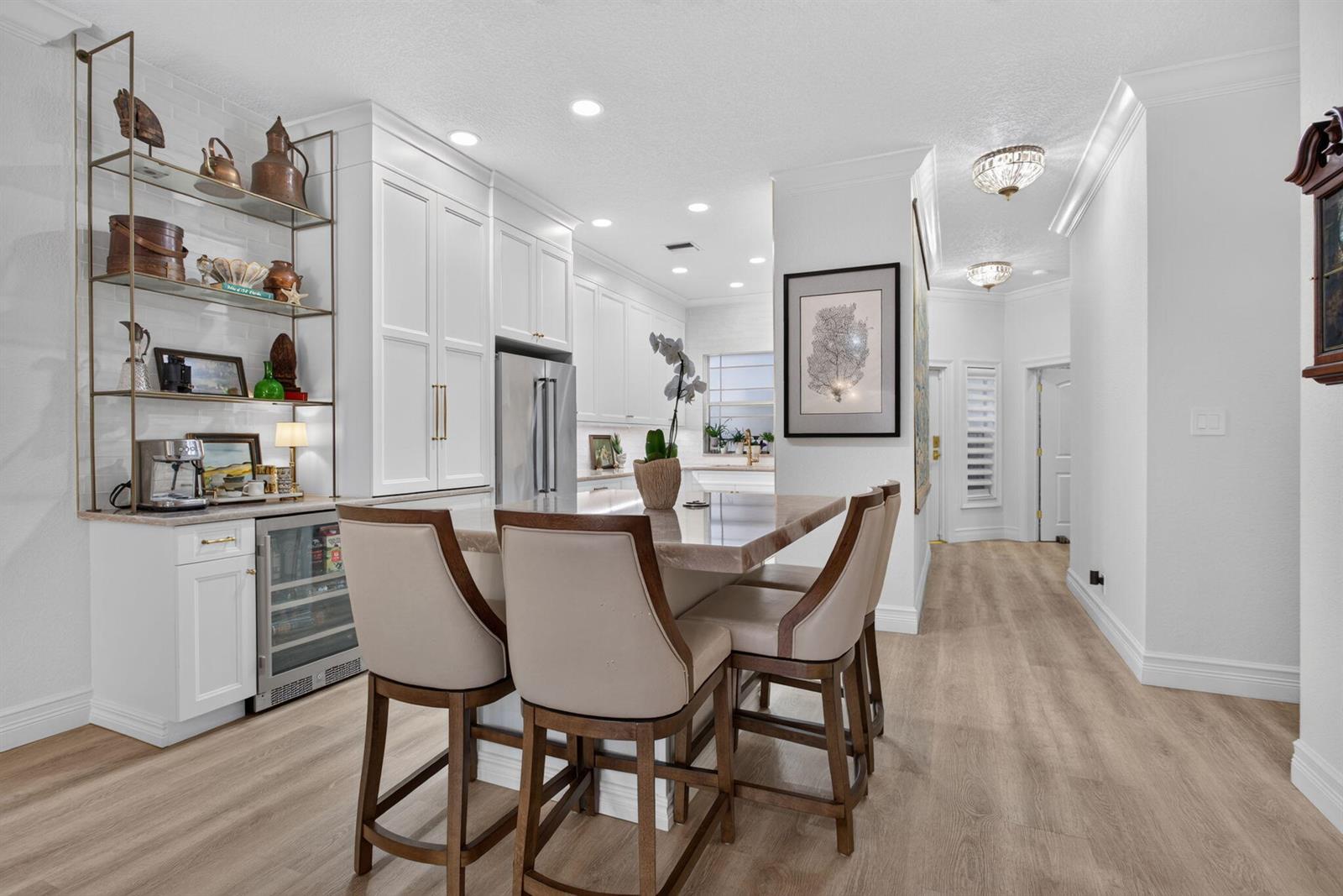 A kitchen features white cabinetry, a stone-topped island with three chairs, and open metal shelving — 2505 NE 2nd Street, Pompano Beach FL 33062, POMPANO BEACH, FL