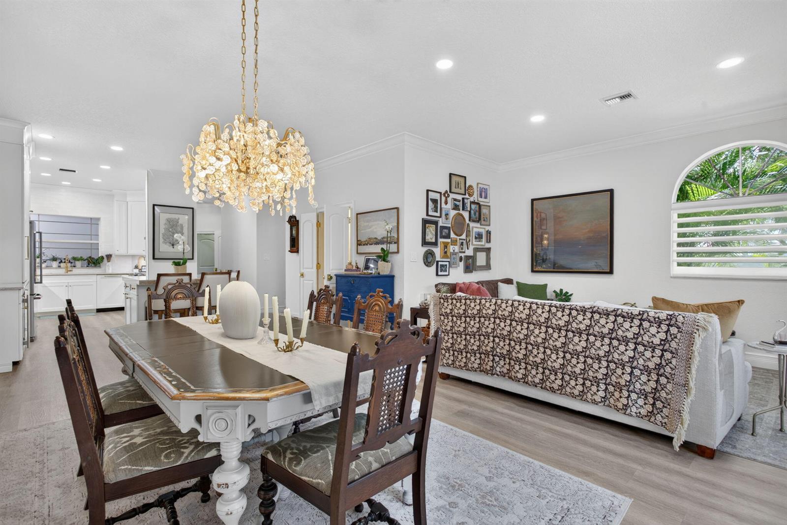 A dining area with a chandelier and wooden chairs opens into a living room space — 2505 NE 2nd Street, Pompano Beach FL 33062, POMPANO BEACH, FL