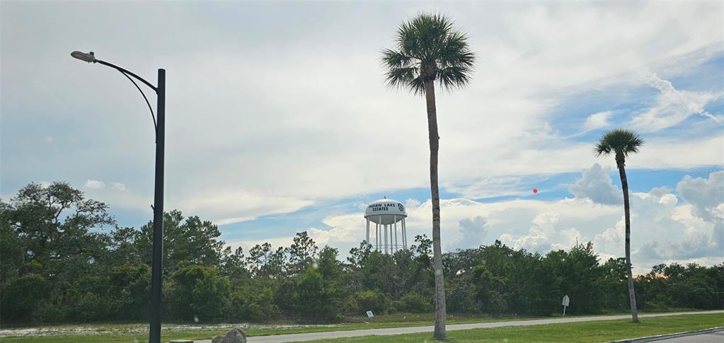 A water tower labeled Indian Lake Estates stands behind trees near two tall palm trees — 1005 PLUMOSA DRIVE, INDIAN LAKE ESTATES, FL