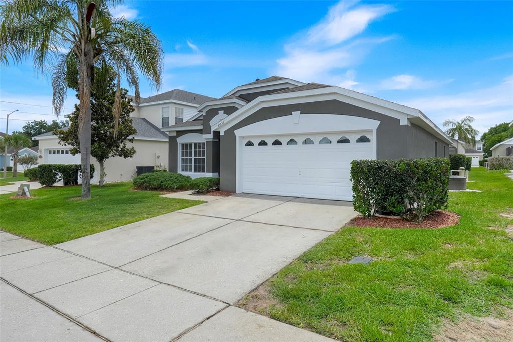A gray single-story house with a white two-car garage and a palm tree in front — 8055 KING PALM CIRCLE, KISSIMMEE, FL