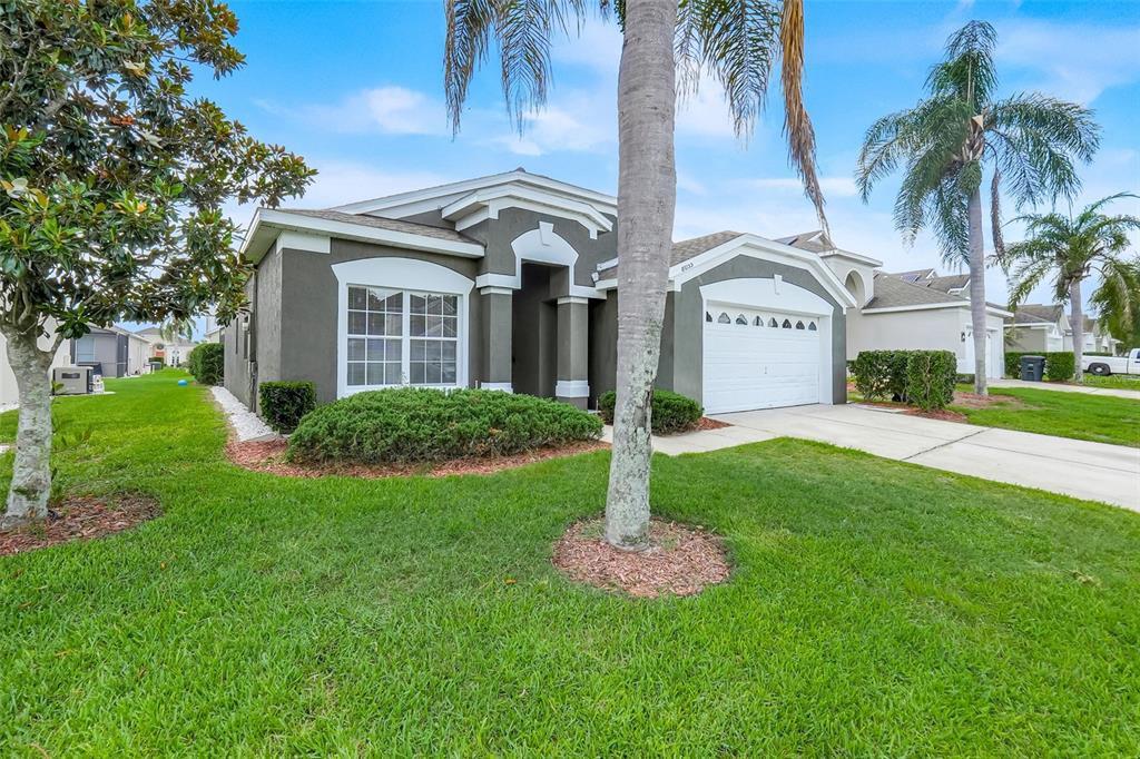 A single-story house with a gray exterior, a two-car garage, and palm trees in front — 8055 KING PALM CIRCLE, KISSIMMEE, FL