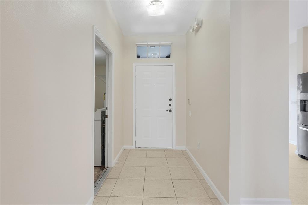 A tiled entryway features a white front door with a transom window and a laundry room — 8055 KING PALM CIRCLE, KISSIMMEE, FL