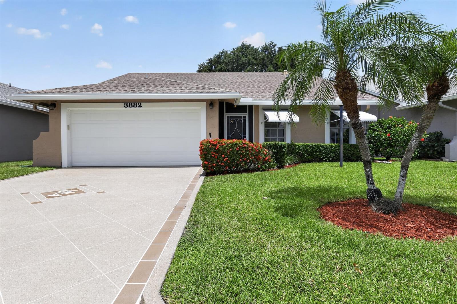 A single-story house with a white garage door, tan stucco walls, and a palm tree — 3882 Dafilee Circle, West Palm Beach FL 33417, WEST PALM BEACH, FL