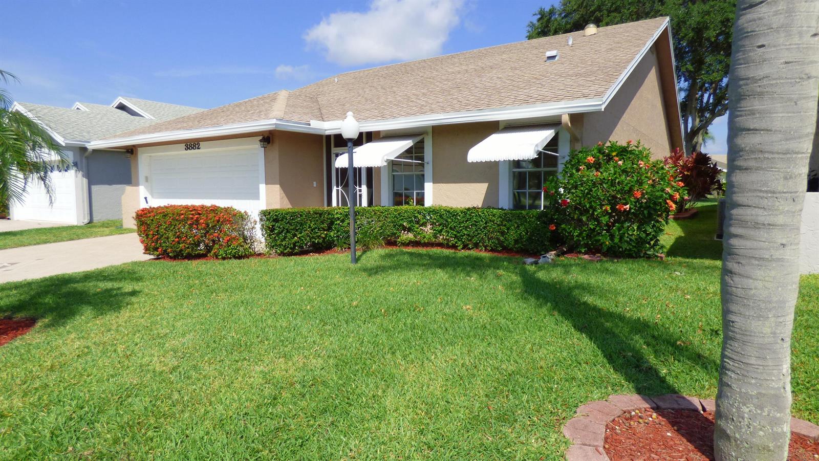 A single-story house with a tan exterior, white garage door, and white window awnings — 3882 Dafilee Circle, West Palm Beach FL 33417, WEST PALM BEACH, FL
