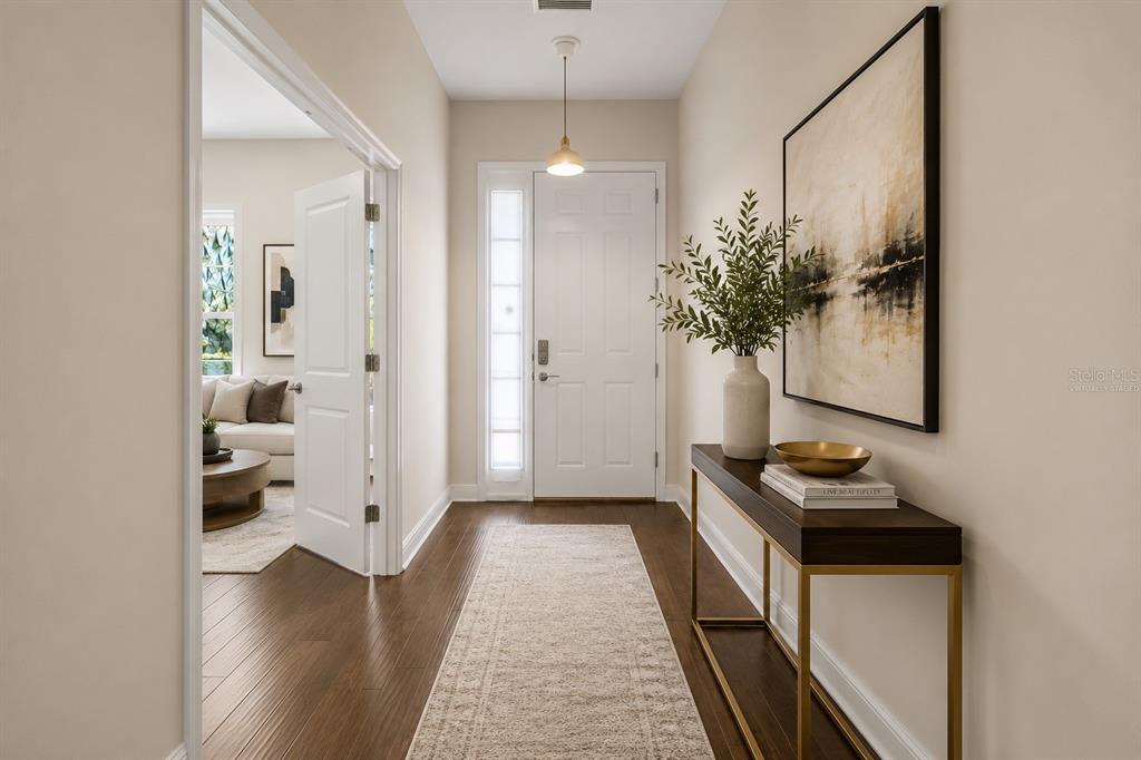 A bright entryway features dark wood floors, a console table, and a white front door — 8724 PEACHTREE PARK COURT, WINDERMERE, FL