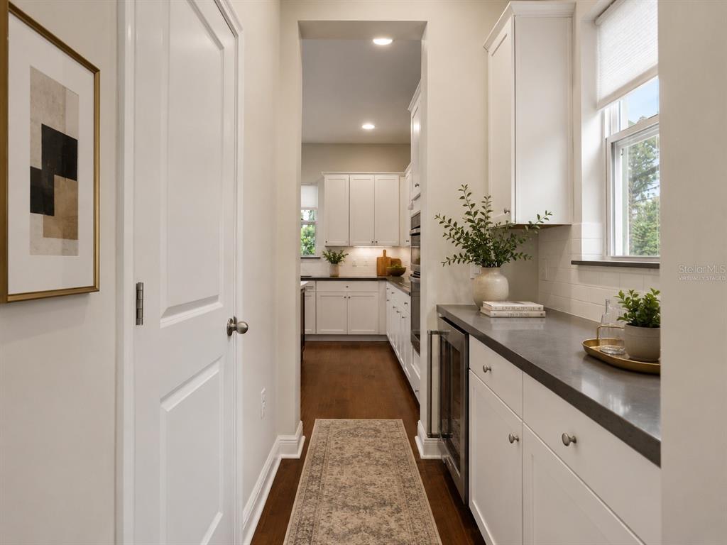 A hallway with a wet bar leads into a white kitchen with dark countertops — 8724 PEACHTREE PARK COURT, WINDERMERE, FL
