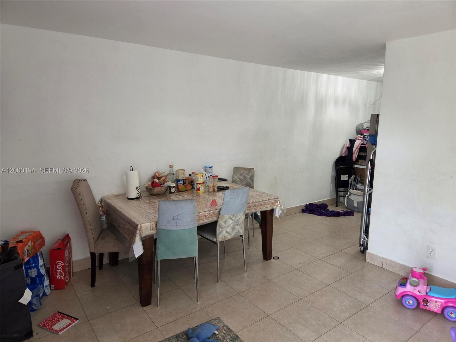 A dining area features a table with mismatched chairs on a tiled floor — 720 SW 6th St, Homestead FL 33030, HOMESTEAD, FL