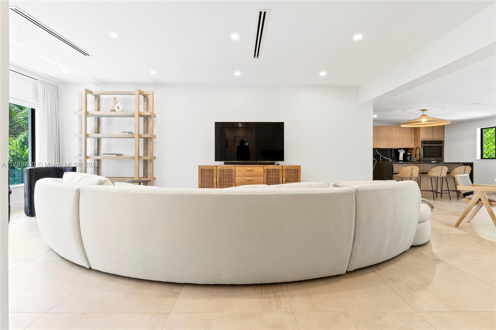 A living room features a curved white sofa, a wooden media console, and an open kitchen — 281 NE 48th Ter, Miami FL 33137, MIAMI, FL