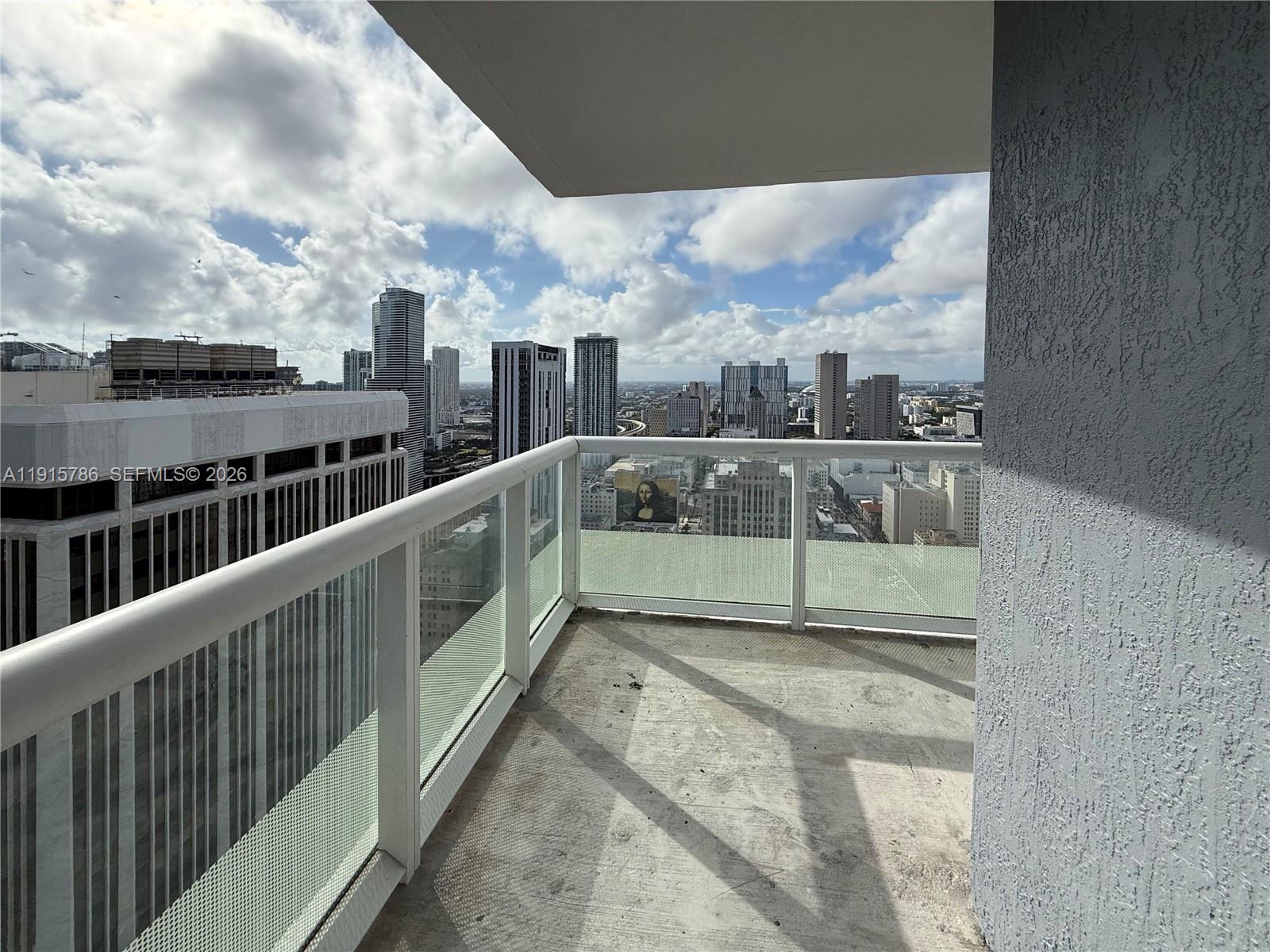 A balcony with a glass railing overlooks a city skyline under a cloudy sky — 50 Biscayne Blvd # 3911, Miami FL 33132, MIAMI, FL