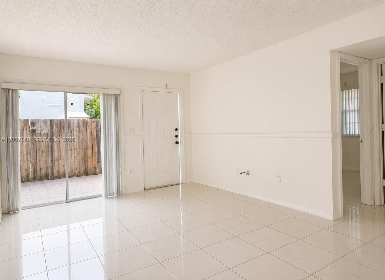 A bright living room features white tile floors, a sliding glass door, and a white door — 15400 SW 81st Cir Ln # 1011, Miami FL 33193, MIAMI, FL