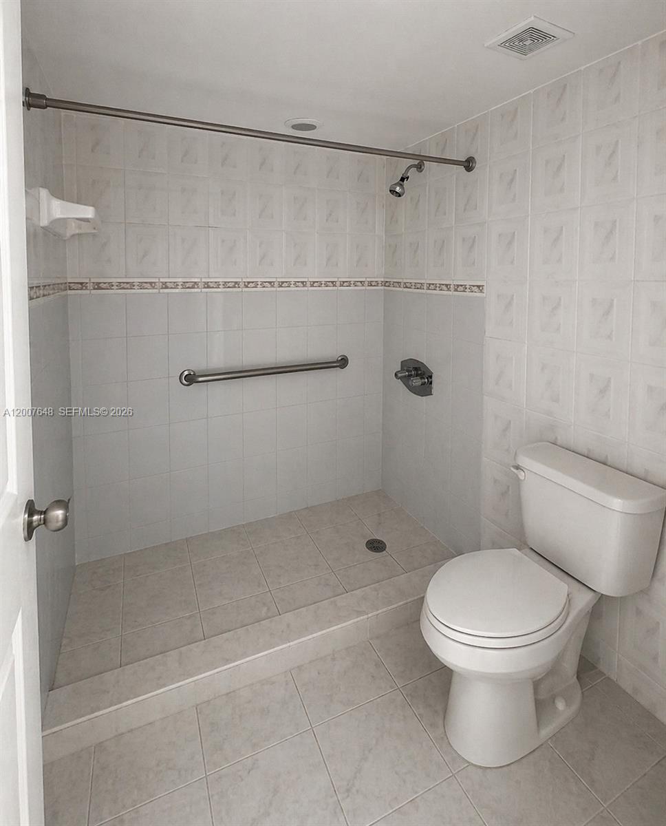 A bathroom features a walk-in tiled shower with a grab bar and a white toilet — 15400 SW 81st Cir Ln # 1011, Miami FL 33193, MIAMI, FL