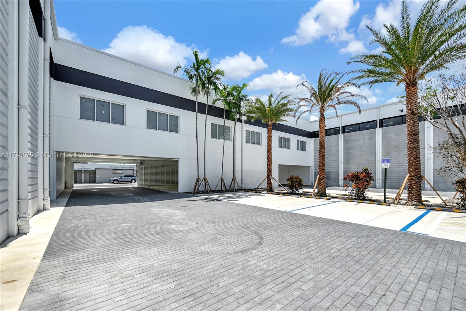 A paved driveway leads to a modern white commercial building with palm trees and parking — 210 NE 68th St # 1, Miami FL 33138, MIAMI, FL