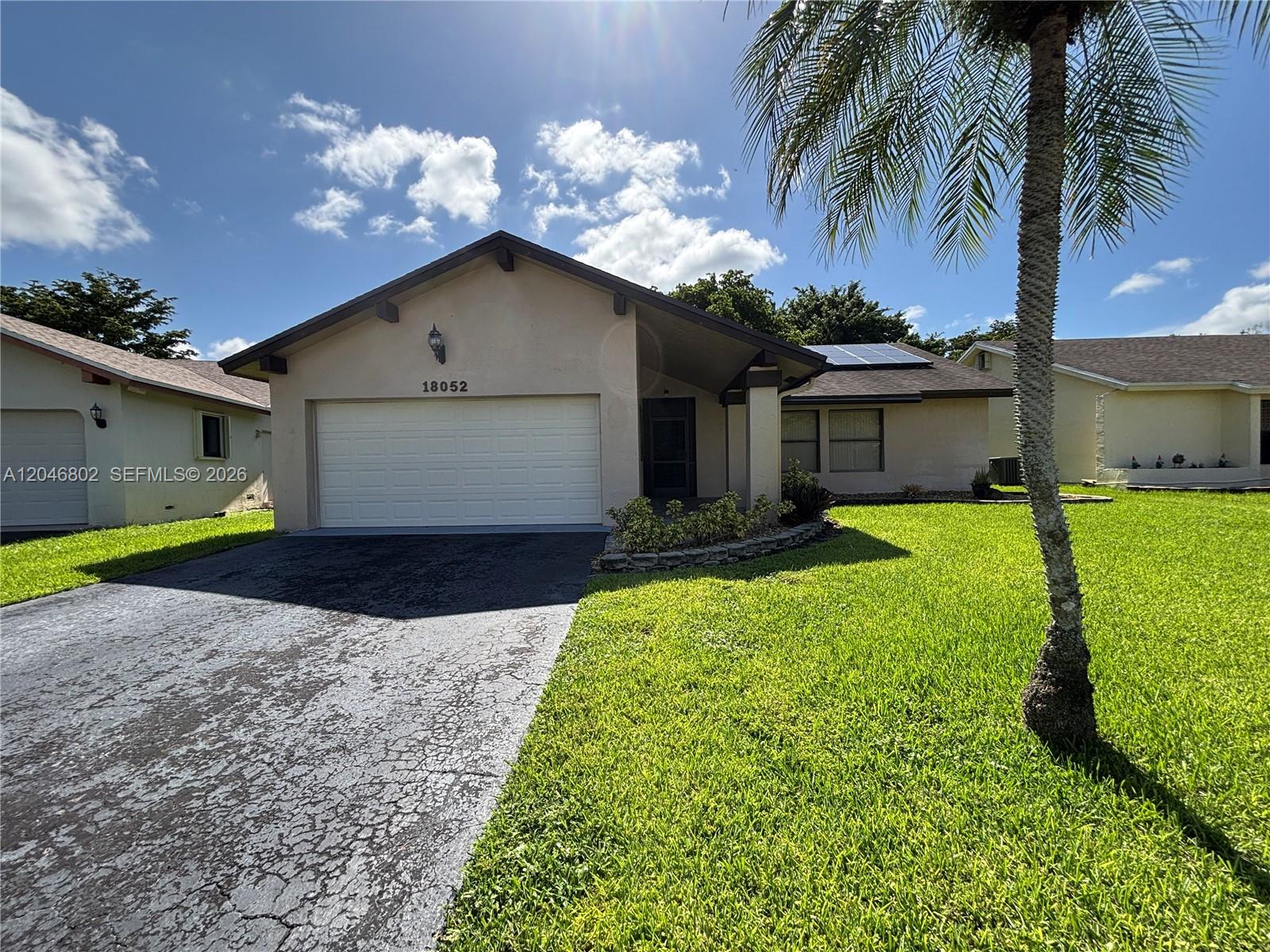 A single-story house with a beige stucco exterior, a two-car garage, and a palm tree — 18052 S 105th Ave S # 18052, Boca Raton FL 33498, BOCA RATON, FL