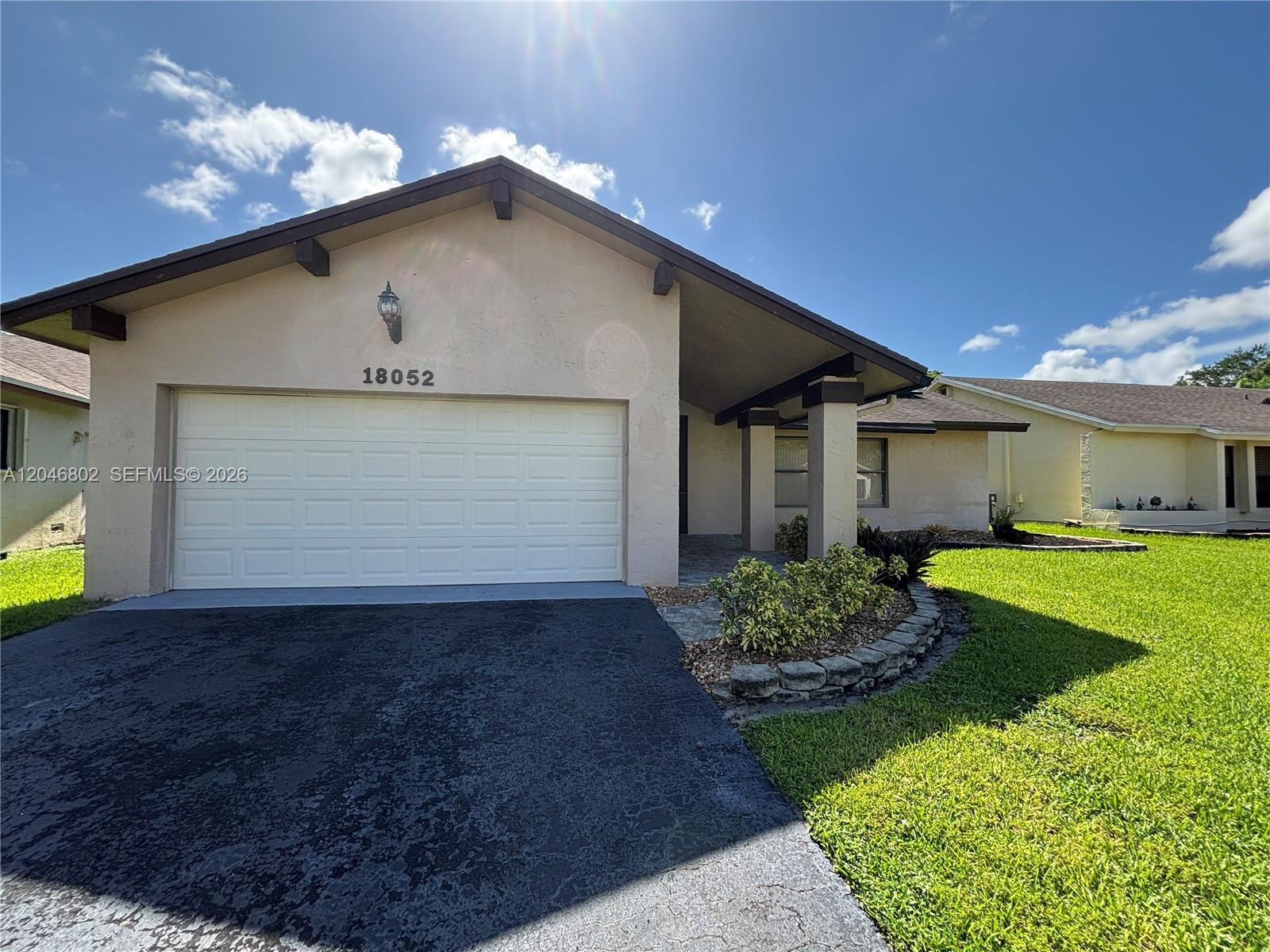 A single-story house features a white garage door, a covered entryway, and a landscaped yard — 18052 S 105th Ave S # 18052, Boca Raton FL 33498, BOCA RATON, FL