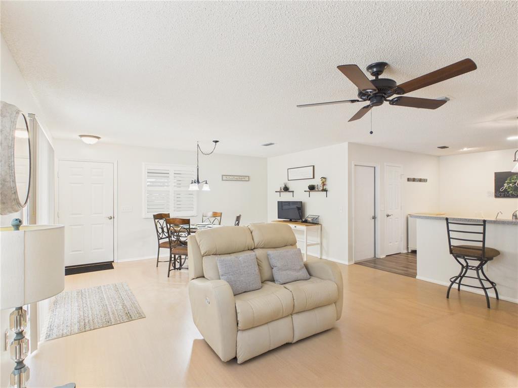 An open-concept living and dining area features light wood flooring, a ceiling fan, and furniture — 746 ANGELITA AVE, THE VILLAGES, FL
