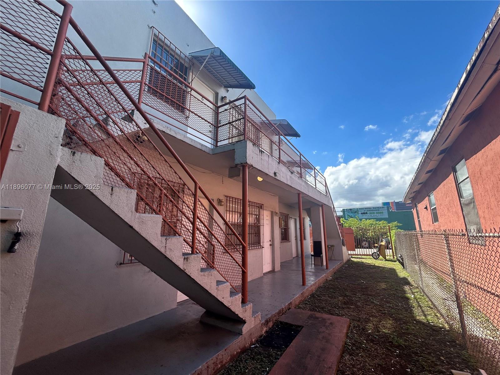 An exterior view of a two-story apartment building with metal stairs and a chain-link fence — 2015 NW 6th Pl, Miami FL 33127, MIAMI, FL