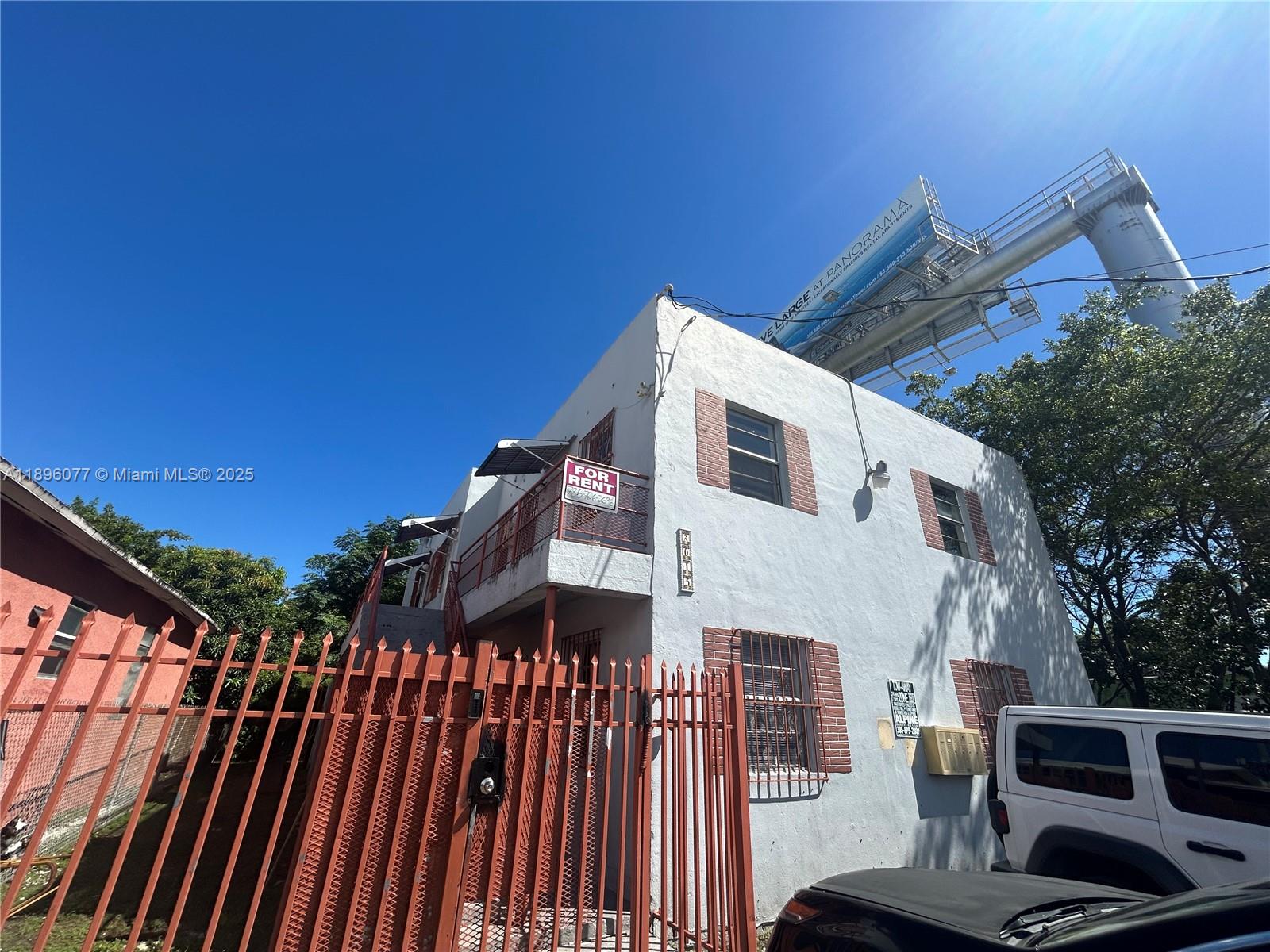 A two-story white stucco building with a red metal fence and a for rent sign — 2015 NW 6th Pl, Miami FL 33127, MIAMI, FL